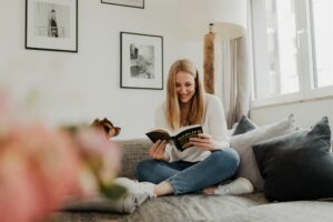 Frau mit Buch und Hund auf Sofa